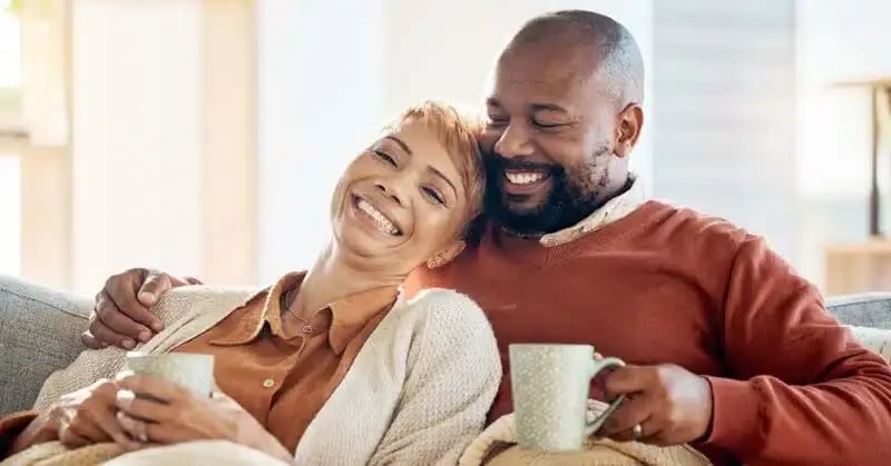 Older couple relaxing on couch with cups of tea